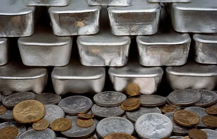 A stock photo of gold and silver coins, with silver ingots.
