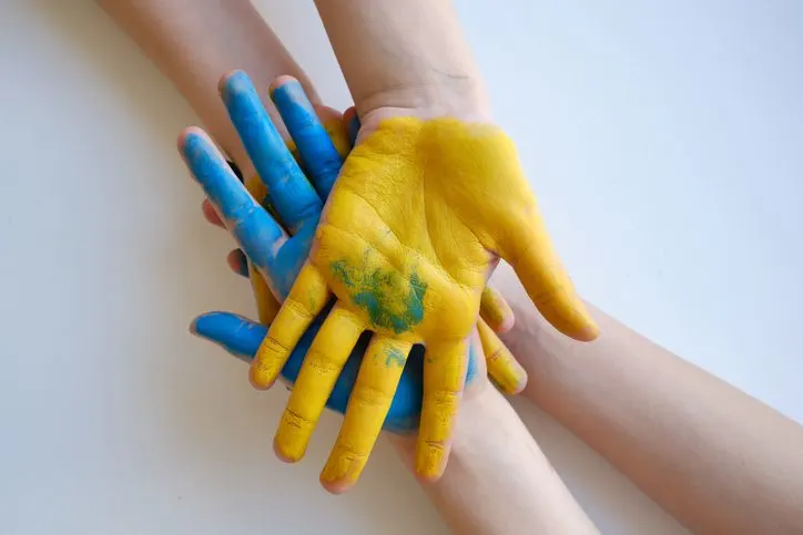 A stock photo of children's hands painted yellow and blue. 