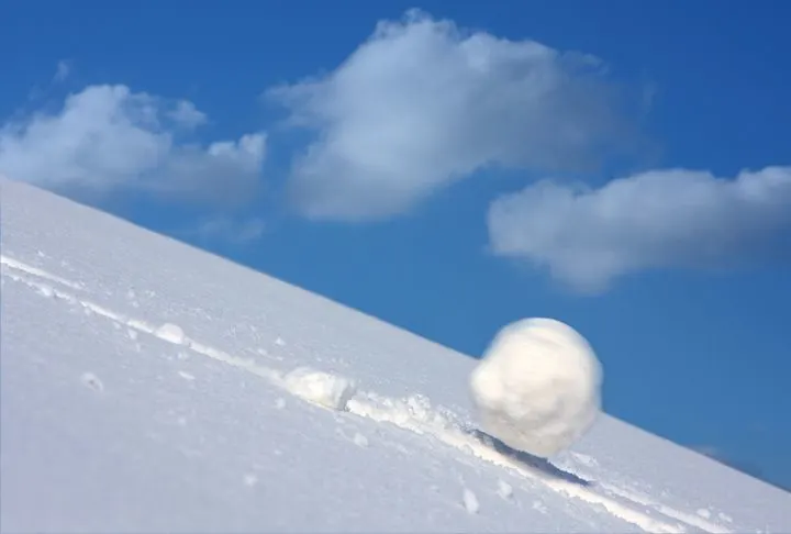 A stock photo of a snowball sliding down the hill. 