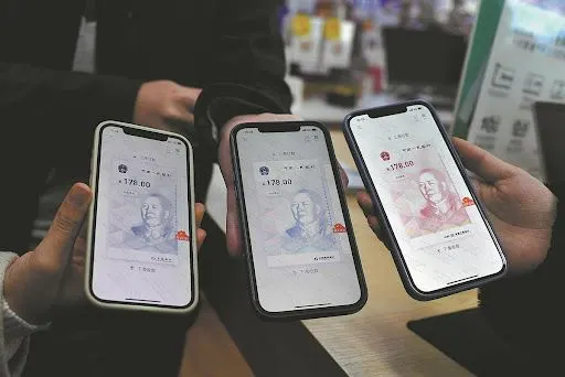 3 people holding 3 smartphones with digital yuan on the screens