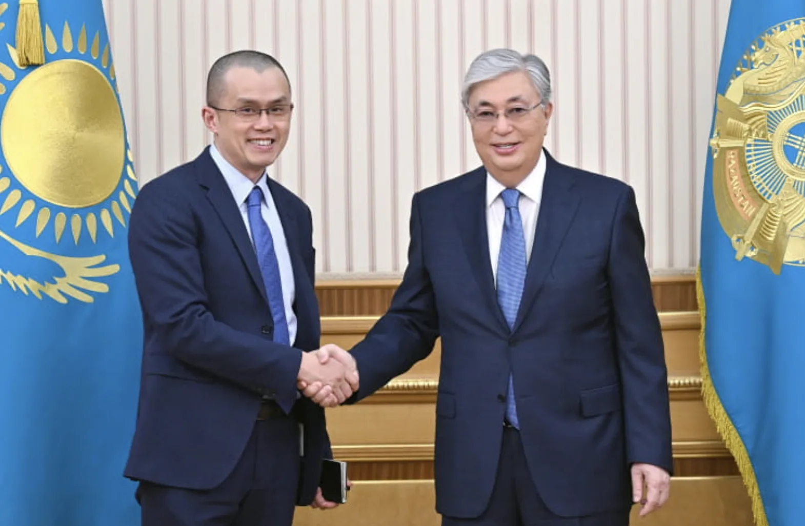 Changpeng Zhao and Kassym-Jomart Tokayev shaking hands at MoU agreement. 