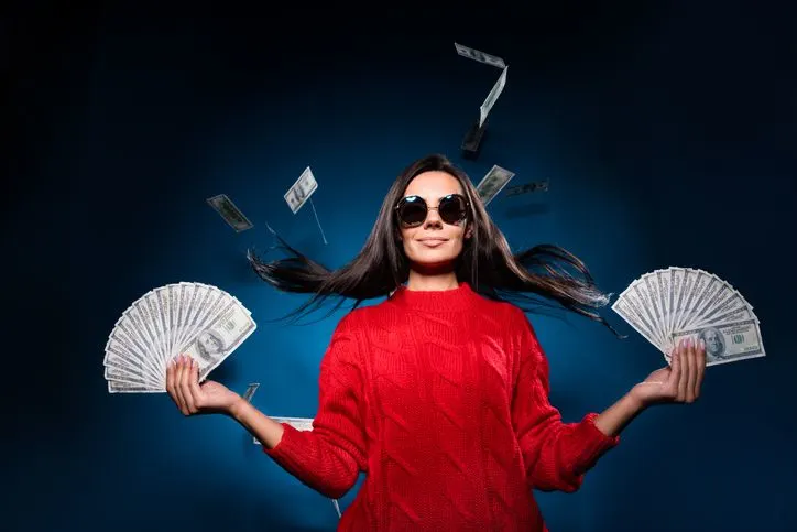 A stock photo of a woman holding a wad of cash in each hand. 