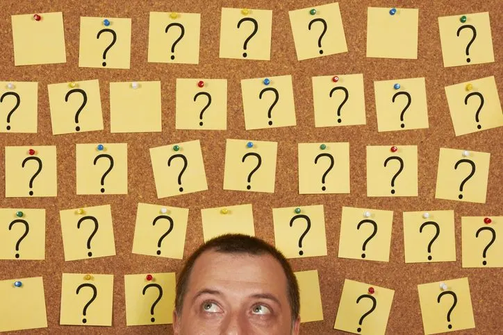 A stock photo of a cropped man's head with the question marks on the background.