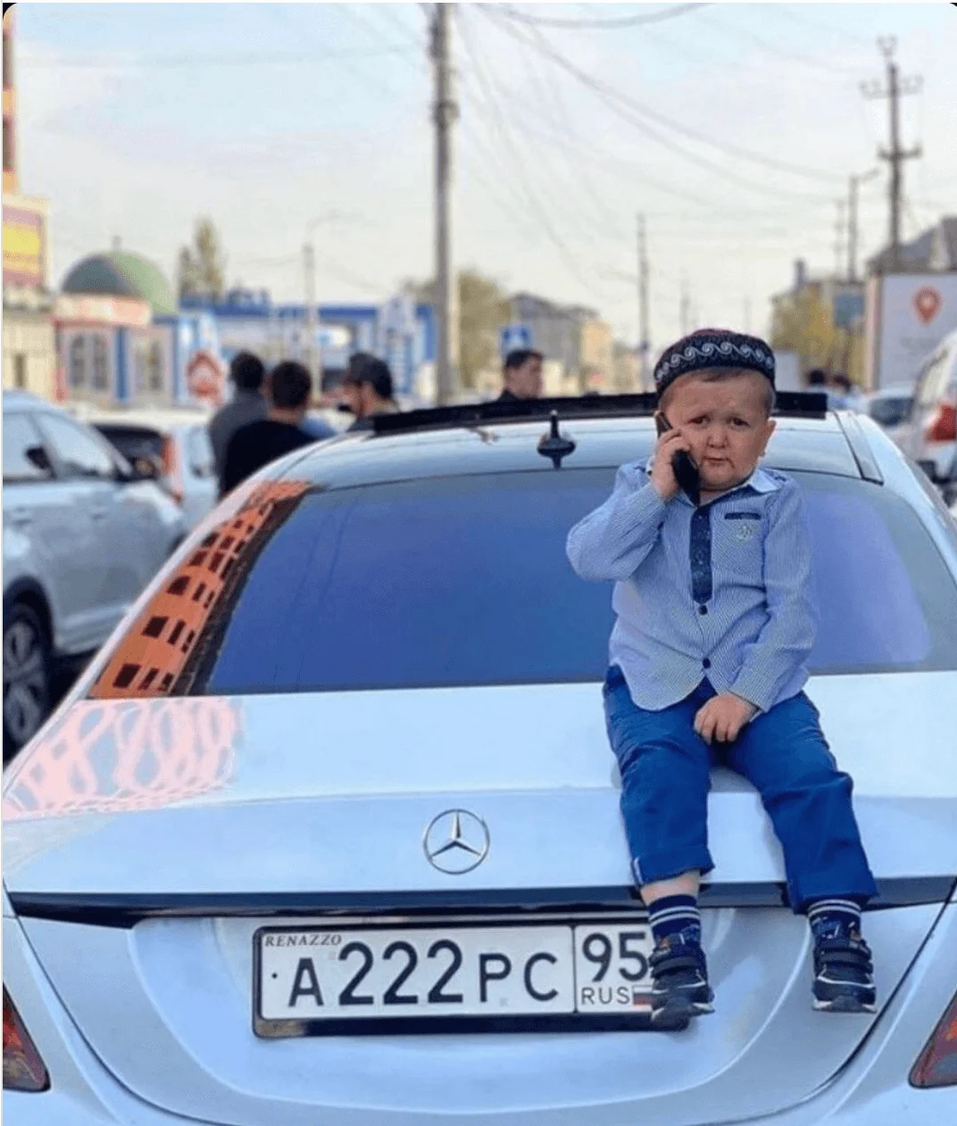 Hasbulla talking over phone sitting on a white car.