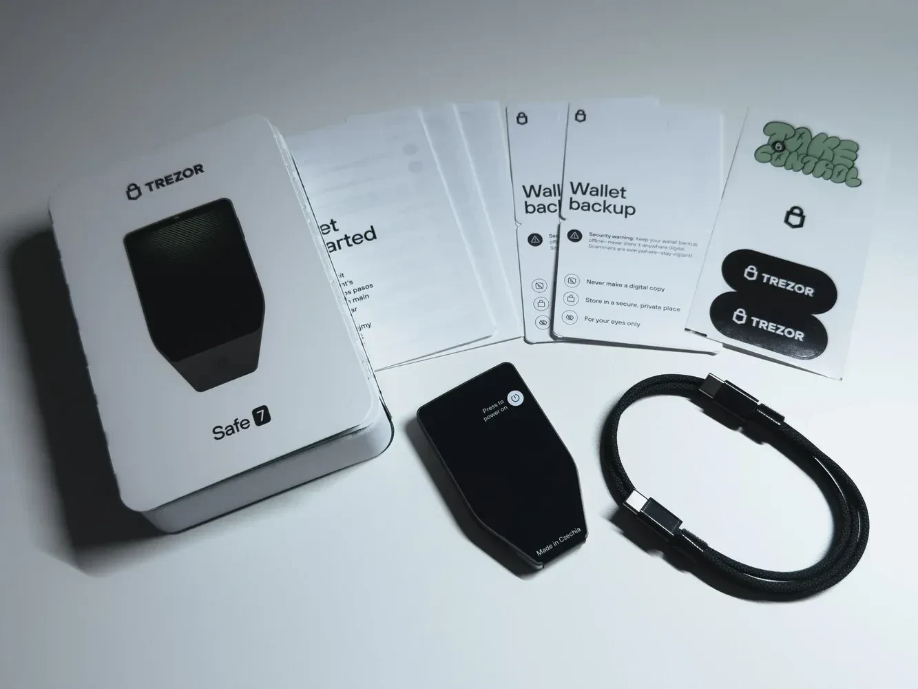 Trezor Safe 7 contents: Charcoal wallet, USB-C cable, 2x recovery cards, guide & stickers.