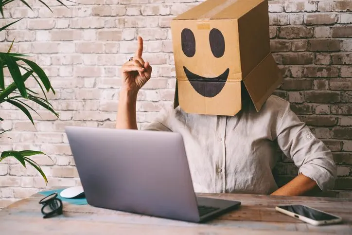 A stock photo of a an anonymous hacker wearing smiling cardboard box. 