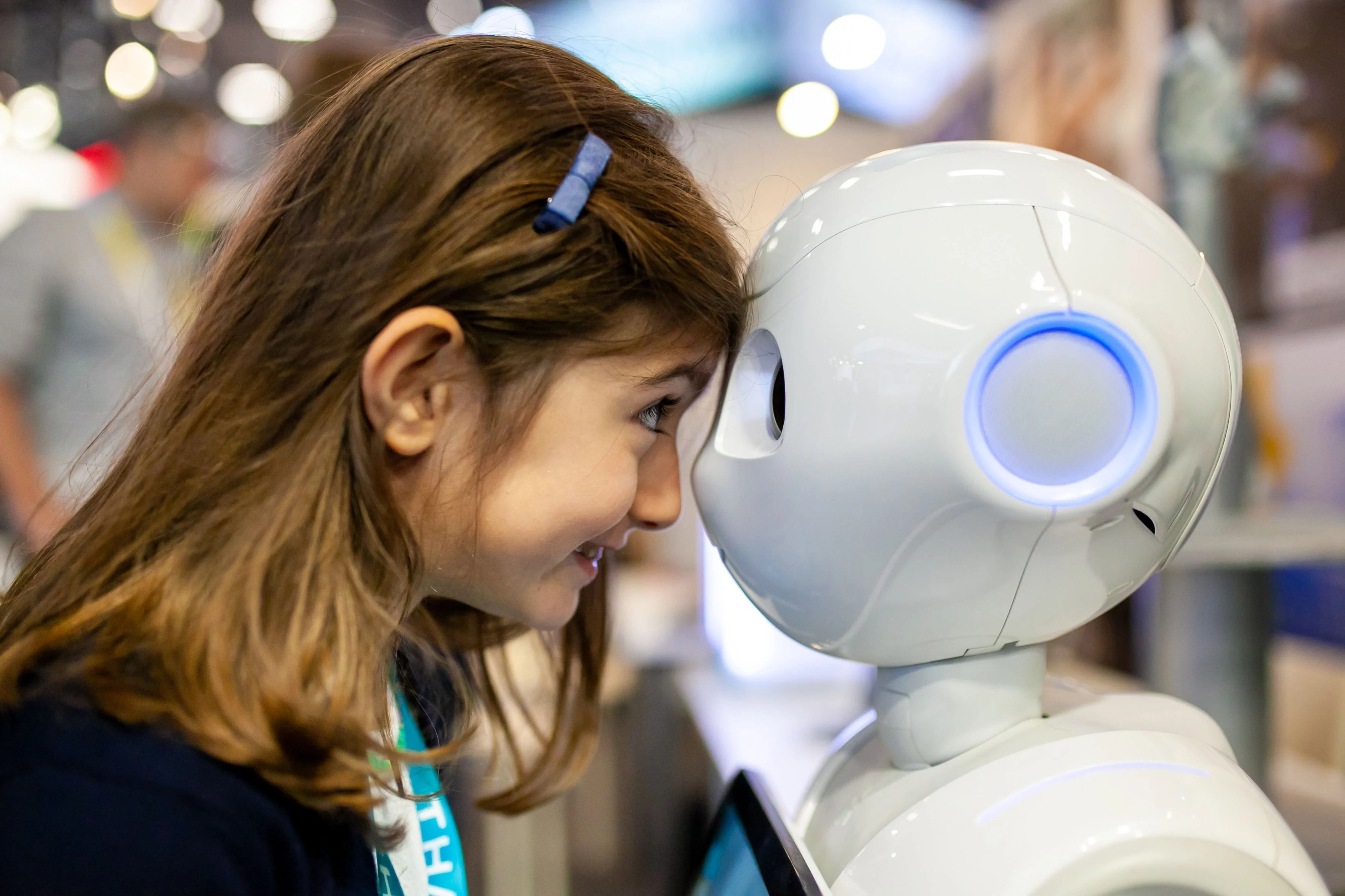 A girl comes face to face with a white anthropomorphic robot at VivaTech